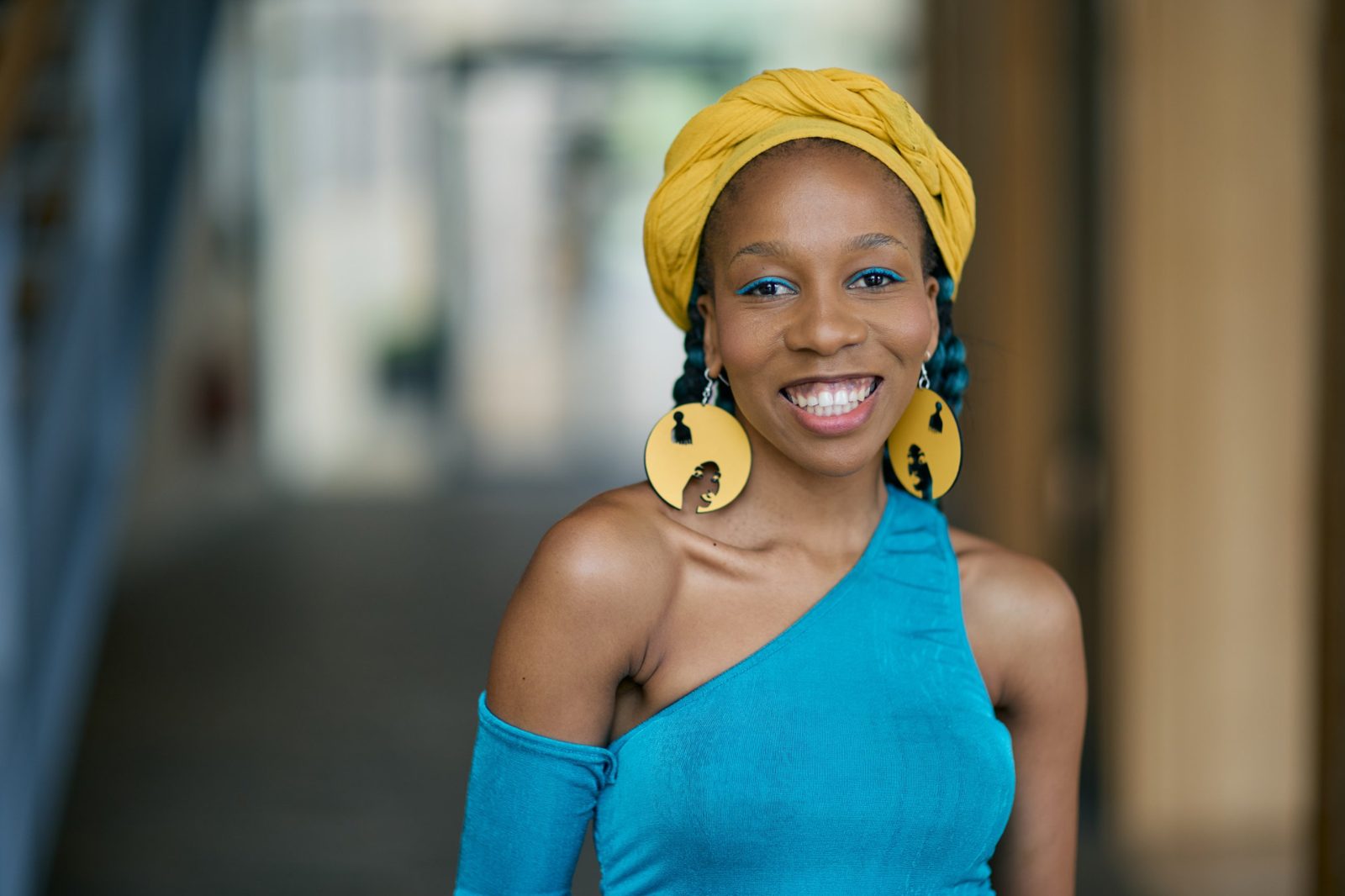 Mantate smiling in a yellow headwrap and teal top